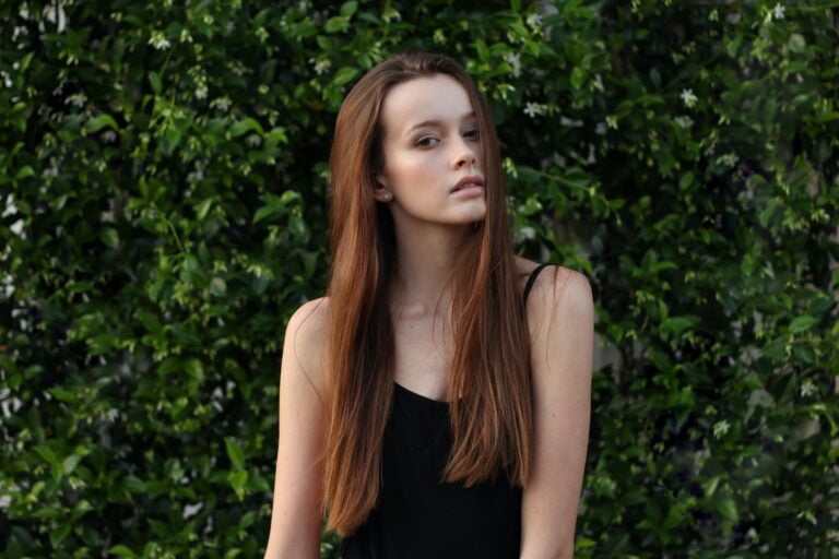 Женщина в топе с бретельками для спагетти перед кустом