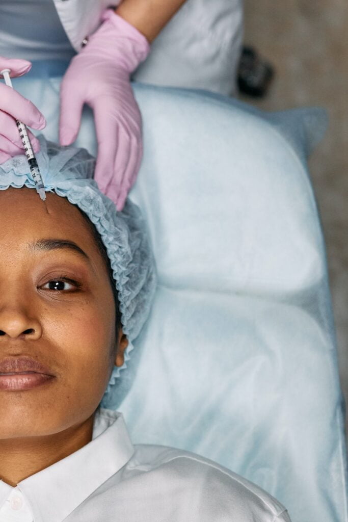 Une femme allongée reçoit du Botox sur le front et un lifting