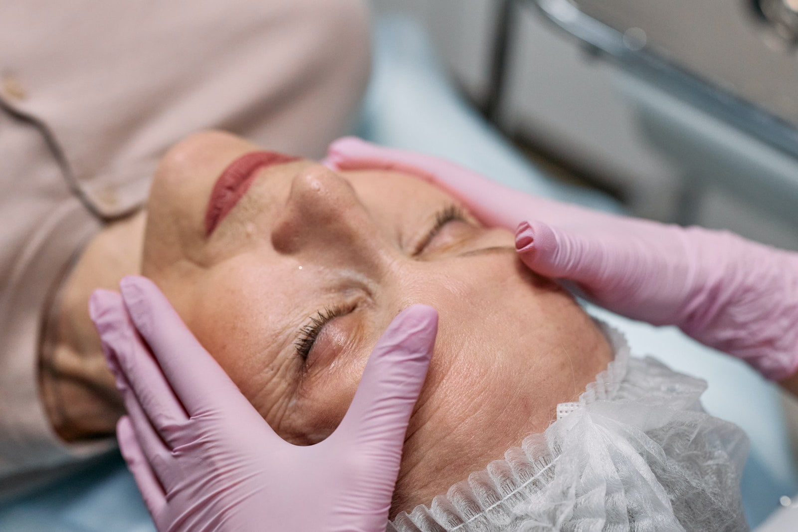 A Person Wearing a Latex Gloves Touching the Face of an Elderly Woman with Her Eye Closed, facial feminization surgery