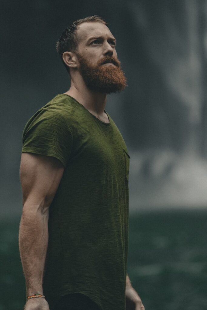 homme portant un t-shirt vert à col rond regardant vers le haut, comment se préparer à une greffe de cheveux