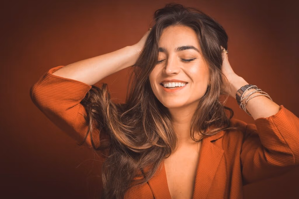 smiling woman in brown top holding hairs, The Benefits of Hair Transplant in Antalya for Women