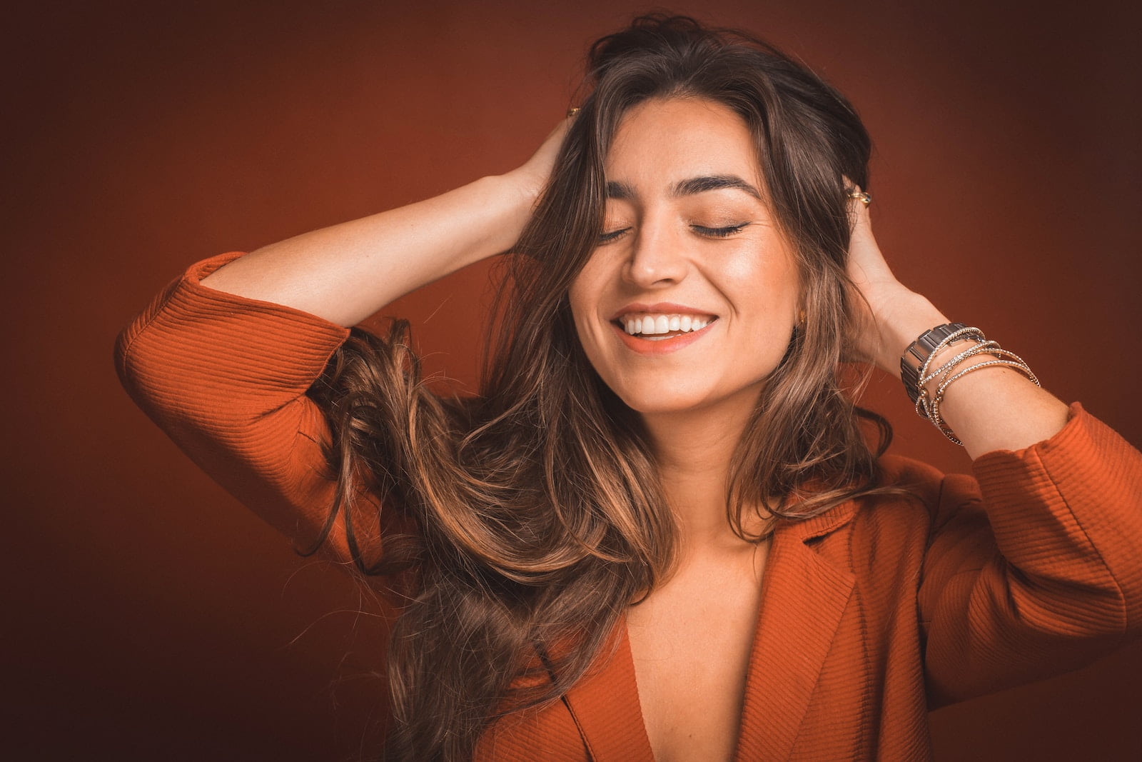smiling woman in brown top holding hairs, The Benefits of Hair Transplant in Antalya for Women