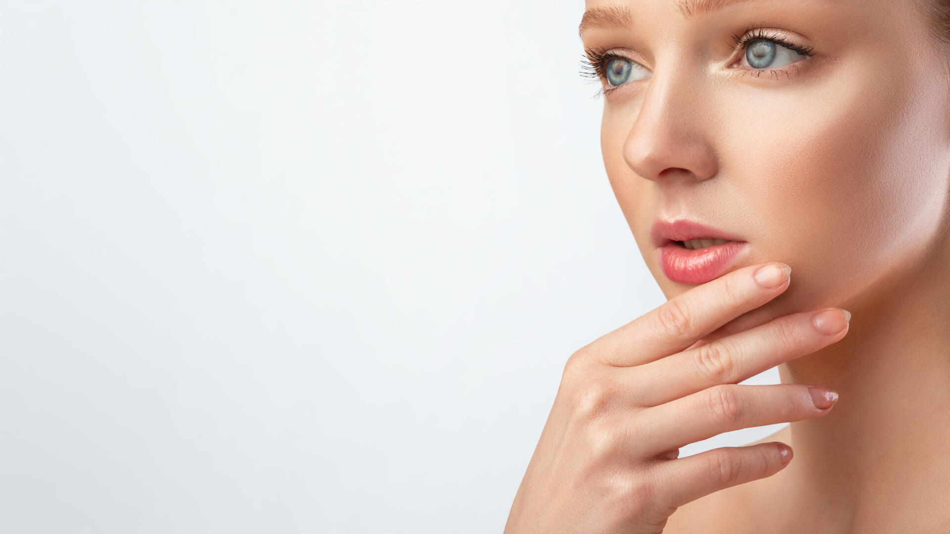 Woman With Perfect Makeup Posing Touching Chin, Gray Background, Cropped, Facial Skincare. Pretty Young Woman With Perfect Makeup Posing Touching Chin And Looking Aside At Free Space For Text Over Gray Studio Background. Panorama, Cropped