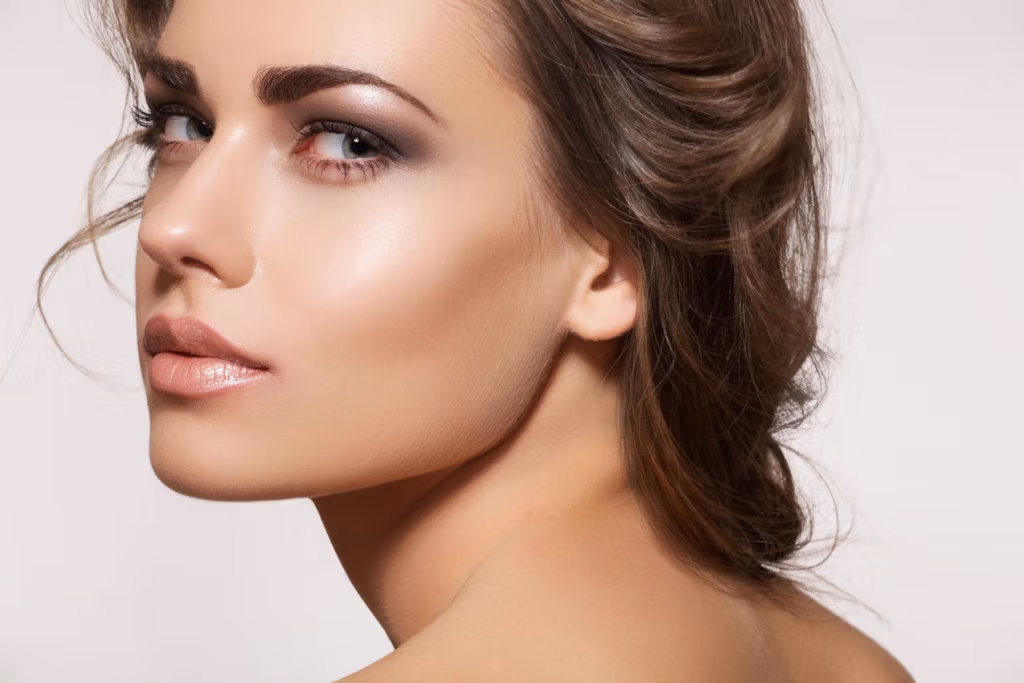 Retrato en primer plano de una mujer con piel tersa y maquillaje sutil, que resalta sus rasgos faciales y su cabello.
