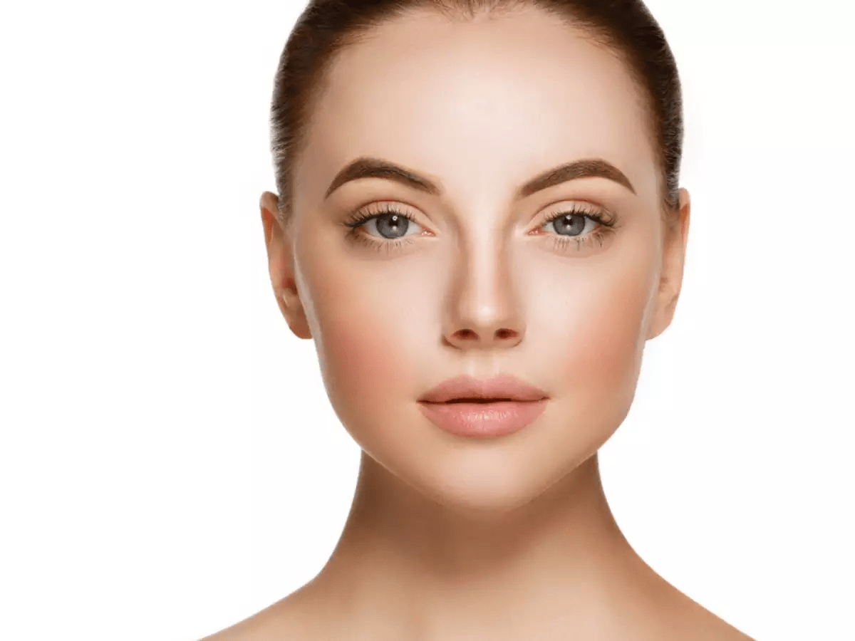 Close-up portrait of a woman with smooth skin, defined eyebrows, and a neutral expression, set against a plain white background.