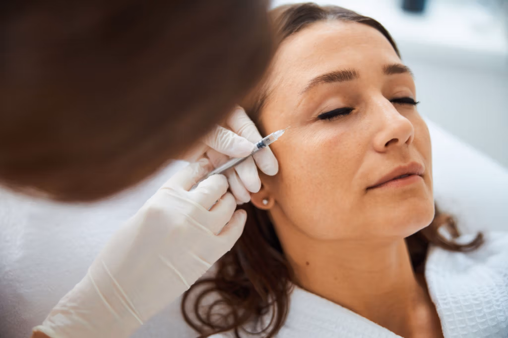 A medical professional administering an injection to a patient's face in a clinical setting.