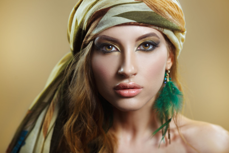 Una mujer con un elegante pañuelo en la cabeza y pendientes, mirando directamente a la cámara.