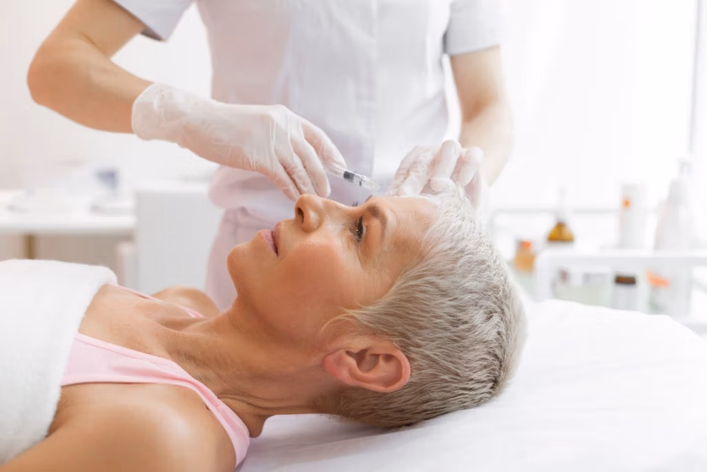 A medical professional administering an injection to a patient's forehead in a clinical setting.