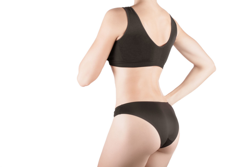 Une femme portant un soutien-gorge de sport noir et des sous-vêtements noirs, vue de dos.