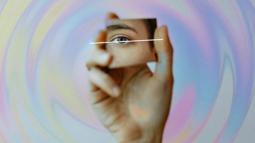 Une image artistique en gros plan de l'œil d'une personne avec un arrière-plan coloré et tourbillonnant et des gestes abstraits de la main encadrant le visage.