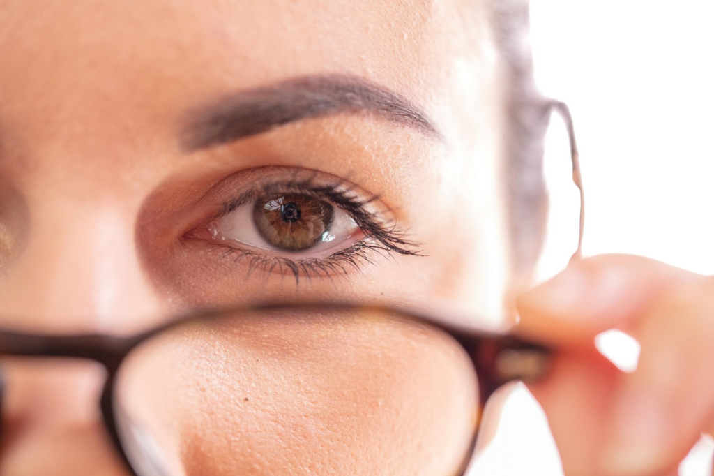 Eine Nahaufnahme des Auges einer Person mit Brille, wobei der Fokus auf dem Auge und einem Teil des Brillengestells liegt.