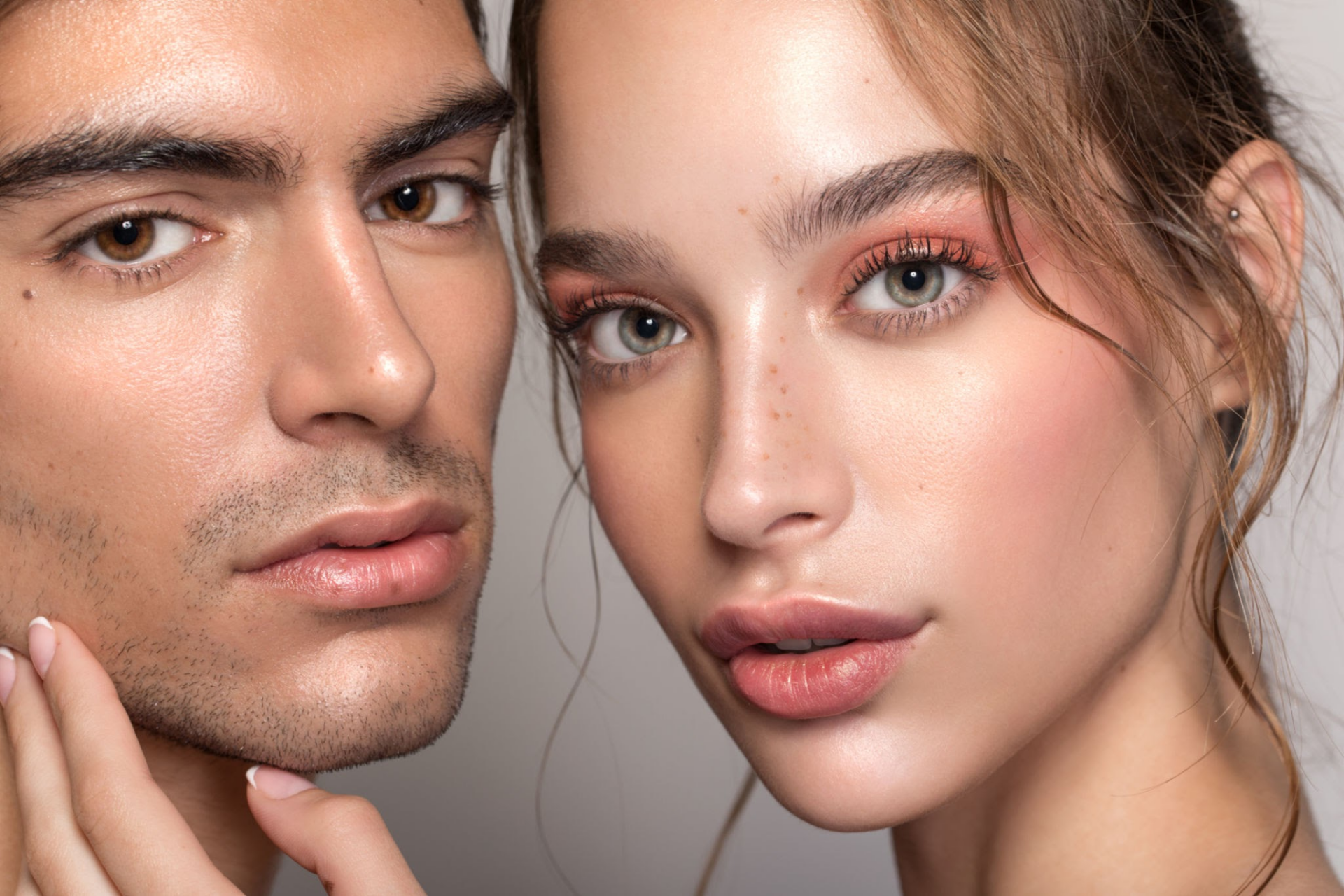 Primo piano di un uomo e una donna con una pelle pulita e dall'aspetto sano, che mette in risalto la bellezza naturale e la cura della pelle. L'uomo posa con una mano sul mento, mentre la donna guarda direttamente in macchina fotografica con un trucco leggero e discreto.