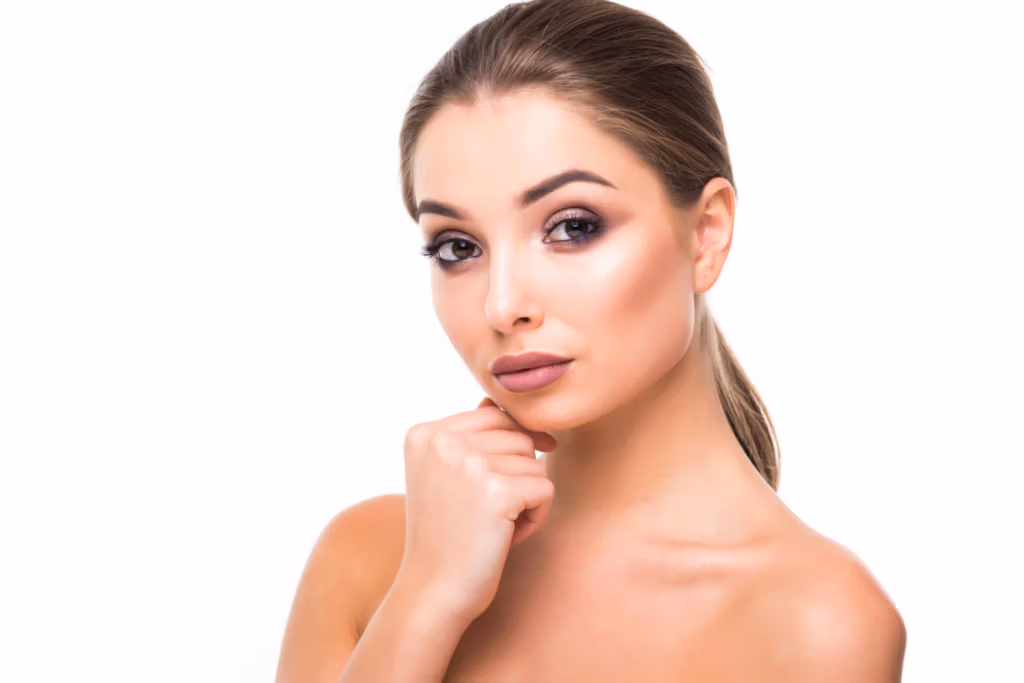 Portrait d'une femme à la peau lisse et au maquillage subtil, regardant pensivement sur le côté, la main posée sur son menton.