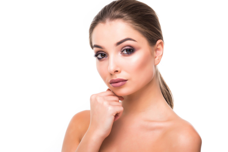 Retrato de una mujer de piel suave y maquillaje sutil, mirando pensativamente hacia un lado, con la mano apoyada en la barbilla.