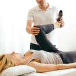 Ein Physiotherapeut hilft einer Patientin, indem er während einer Rehabilitationssitzung ihr Bein anhebt.