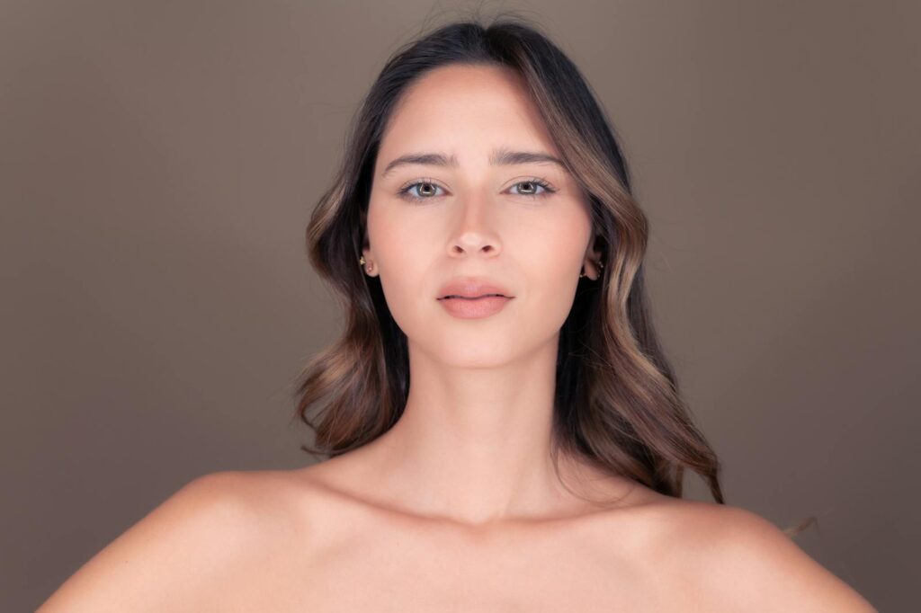 Studio portrait of a beautiful brunette woman with delicate features and a calm expression.