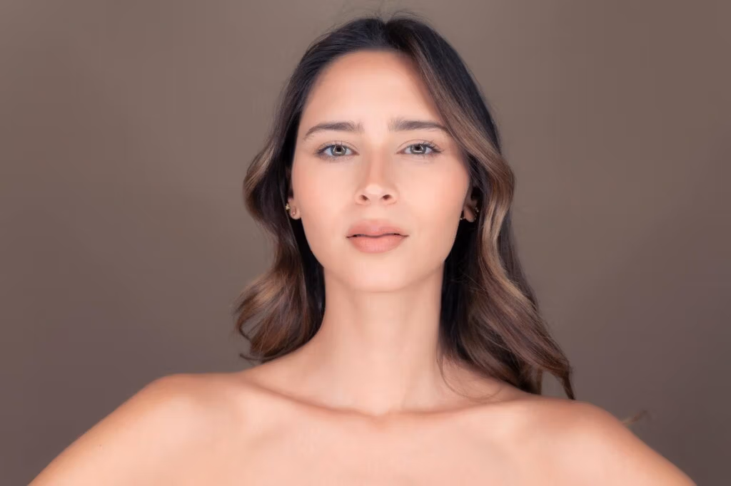 Studio portrait of a beautiful brunette woman with delicate features and a calm expression.