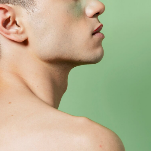 Side profile of a man with a clean-shaven face and short hair, looking upwards against a light green background.