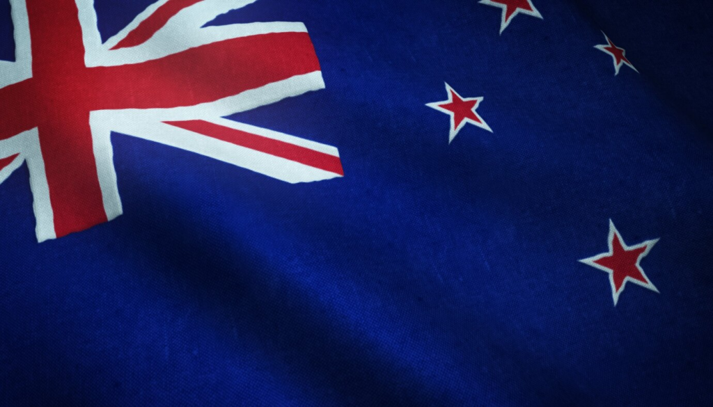 A close-up of the New Zealand flag, featuring a blue background with the Union Jack in the upper left corner and four red stars with white borders representing the Southern Cross constellation.