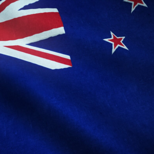 A close-up of the New Zealand flag, featuring a blue background with the Union Jack in the upper left corner and four red stars with white borders representing the Southern Cross constellation.