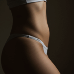 Close-up of a person's torso wearing a white garment with a visible elastic waistband against a dark background.