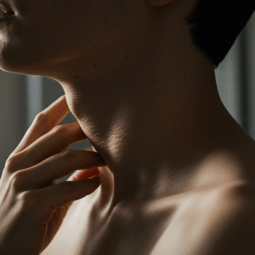 Een close-up van een persoon die zijn nek aanraakt met zijn hand.