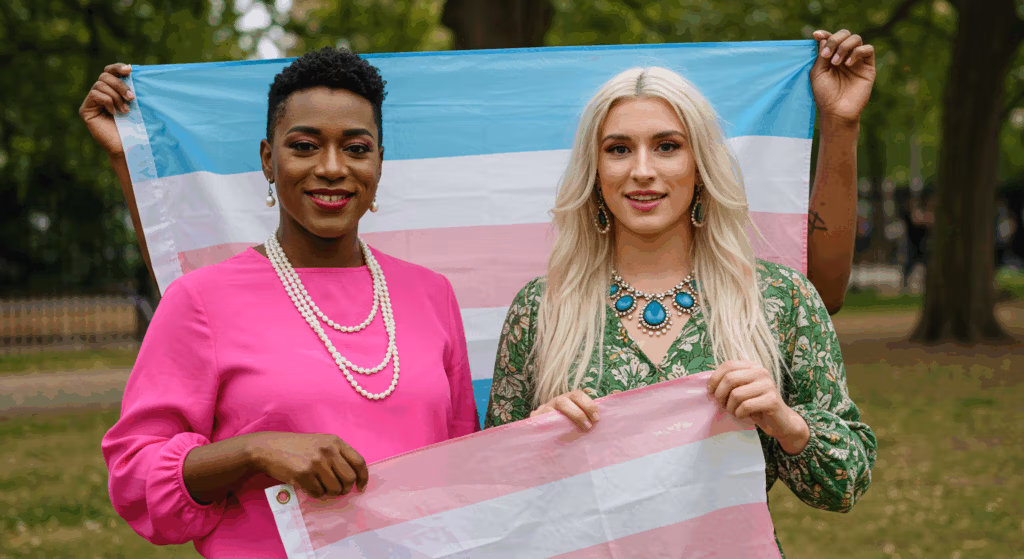 Two people holding a trans pride flag in a park