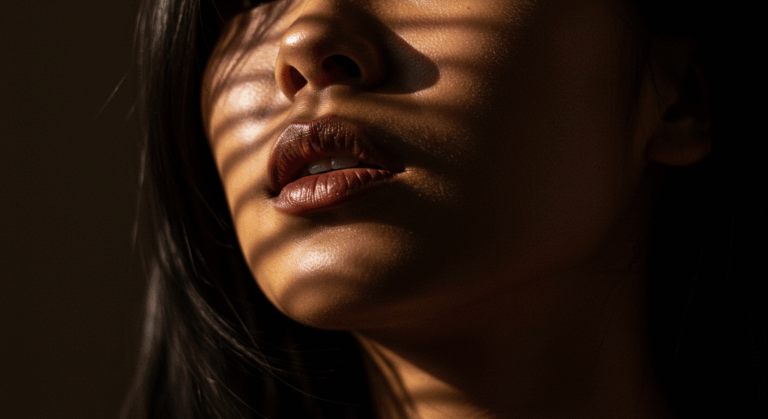 Un portrait en gros plan d'une personne avec un éclairage chaud et doré mettant en valeur ses lèvres et ses pommettes, créant une atmosphère dramatique et sensuelle.