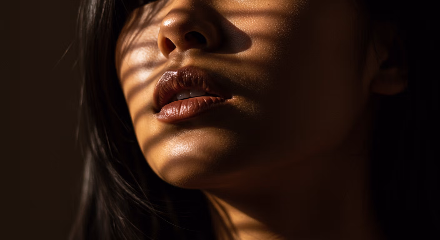 Un portrait en gros plan d'une personne avec un éclairage chaud et doré mettant en valeur ses lèvres et ses pommettes, créant une atmosphère dramatique et sensuelle.