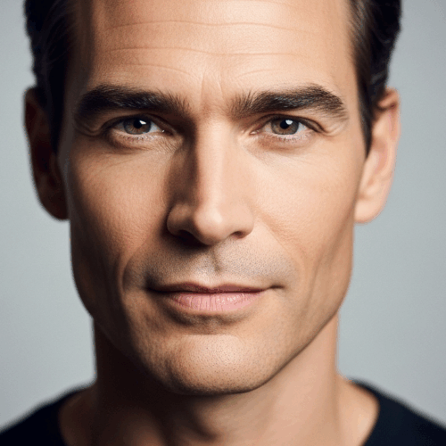 A close-up portrait of a man with short, dark hair and a serious expression, looking directly at the camera against a plain background.