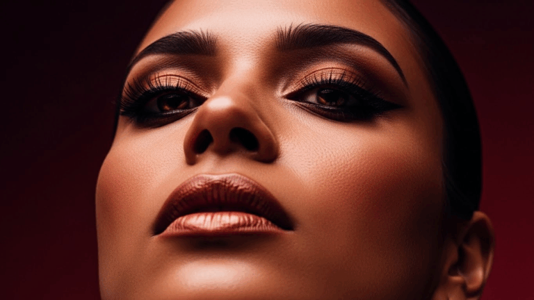 Un retrato en primer plano de una persona con un maquillaje de ojos llamativo y lápiz labial rojo, mirando directamente a la cámara con un fondo oscuro.