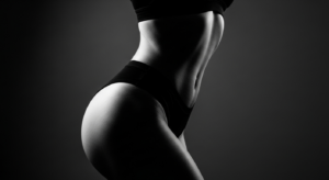A black and white close-up shot of a fit woman's toned torso and hips, showcasing a healthy, slim physique.