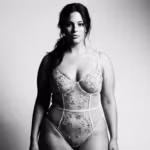 Een zwart-witportret van een zelfverzekerde vrouw met een natuurlijke uitstraling, gekleed in een elegant kanten bodysuit met bloemenprint.