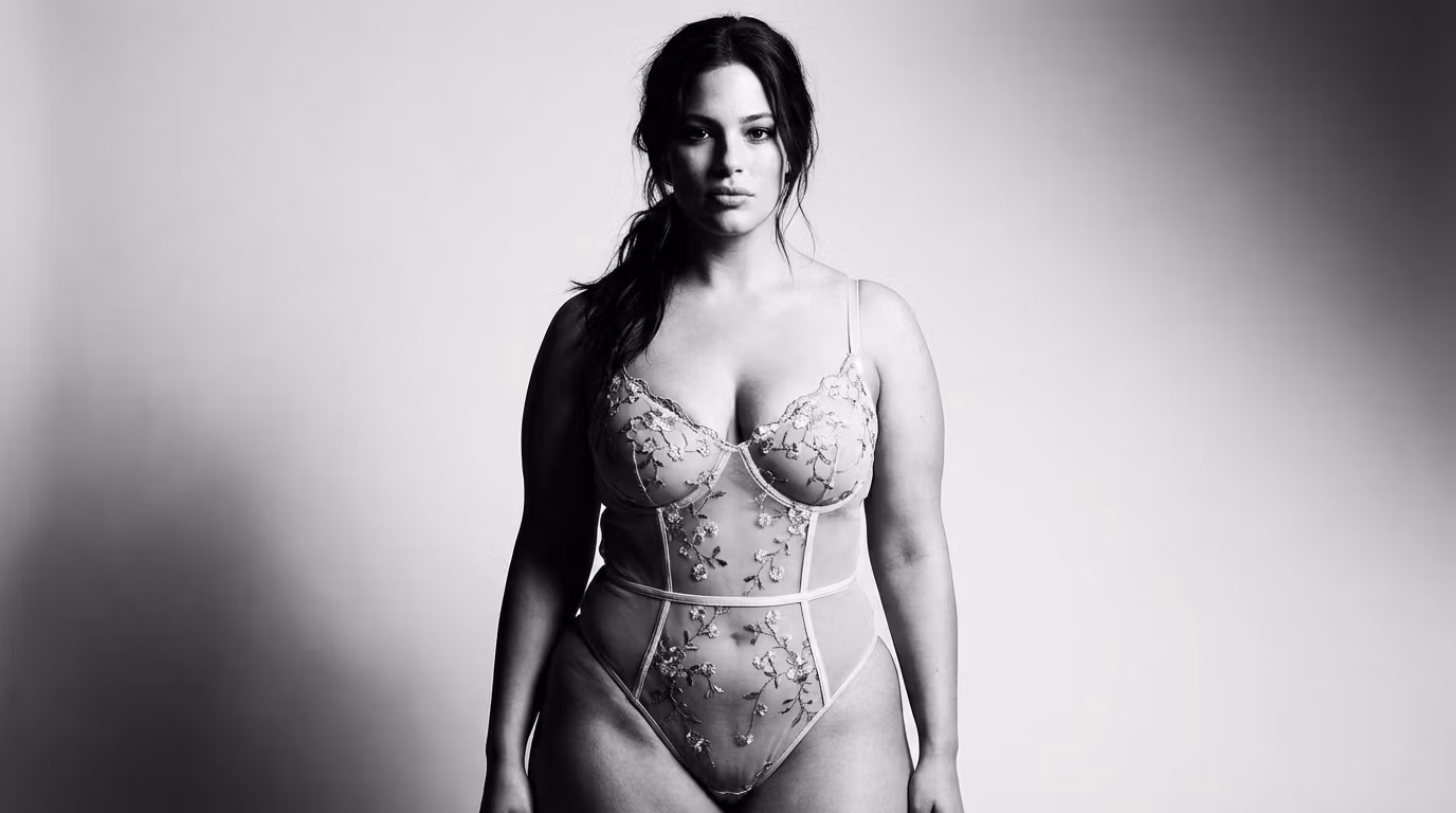 Een zwart-witportret van een zelfverzekerde vrouw met een natuurlijke uitstraling, gekleed in een elegant kanten bodysuit met bloemenprint.