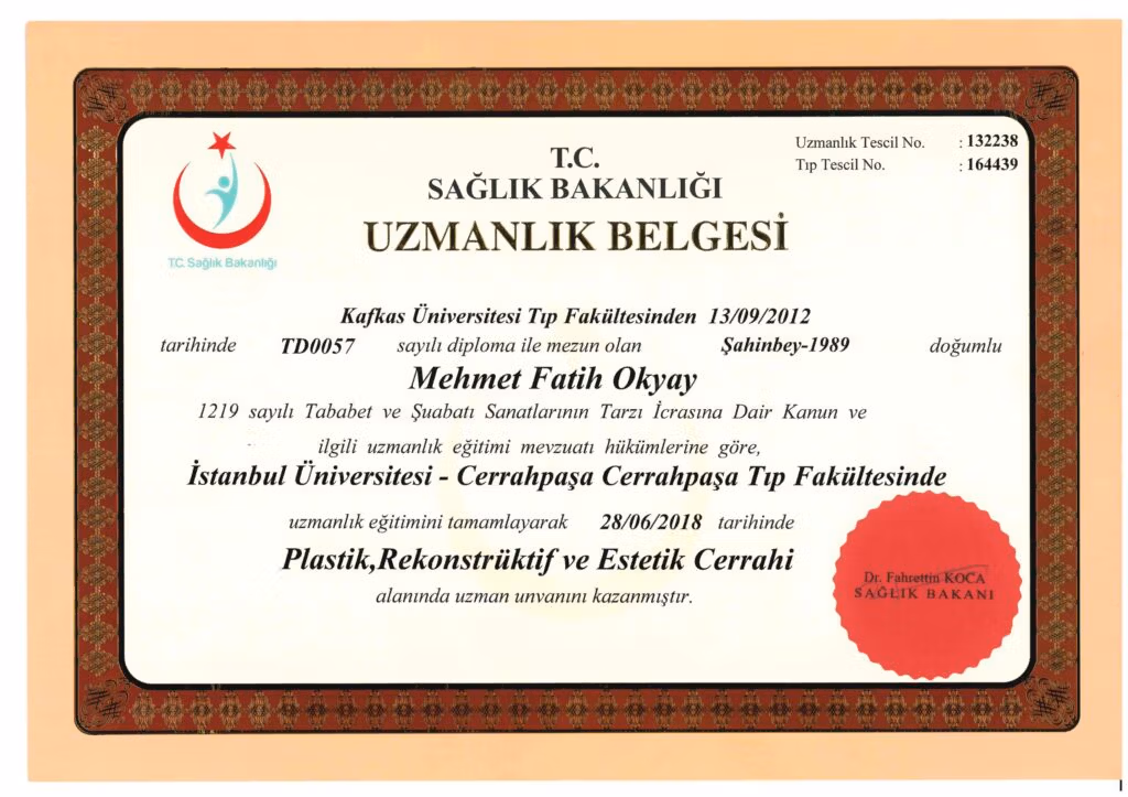 Türkiye Cumhuriyeti Sağlık Bakanlığı tarafından verilen, süslü çerçeveli ve kırmızı mühürlü resmi bir Tıp Uzmanlık Belgesi. Bu belge, Mehmet Fatih Okyay'ın 28 Haziran 2018 tarihinde İstanbul Üniversitesi Cerrahpaşa Tıp Fakültesi'nde Plastik, Rekonstrüktif ve Estetik Cerrahi uzmanlık eğitimini tamamladığını belgelemektedir. Belgede ayrıca Kafkas Üniversitesi'nden (2012) tıp fakültesi mezuniyet bilgileri, kayıt numaraları ve Sağlık Bakanı Dr. Fahrettin Koca'nın adı yer almaktadır.