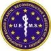 Cirkelvormig logo van de European Board of Plastic, Reconstructive & Aesthetic Surgery (UEMS) met een blauwe achtergrond, gele sterren en een wit medisch symbool in het midden.